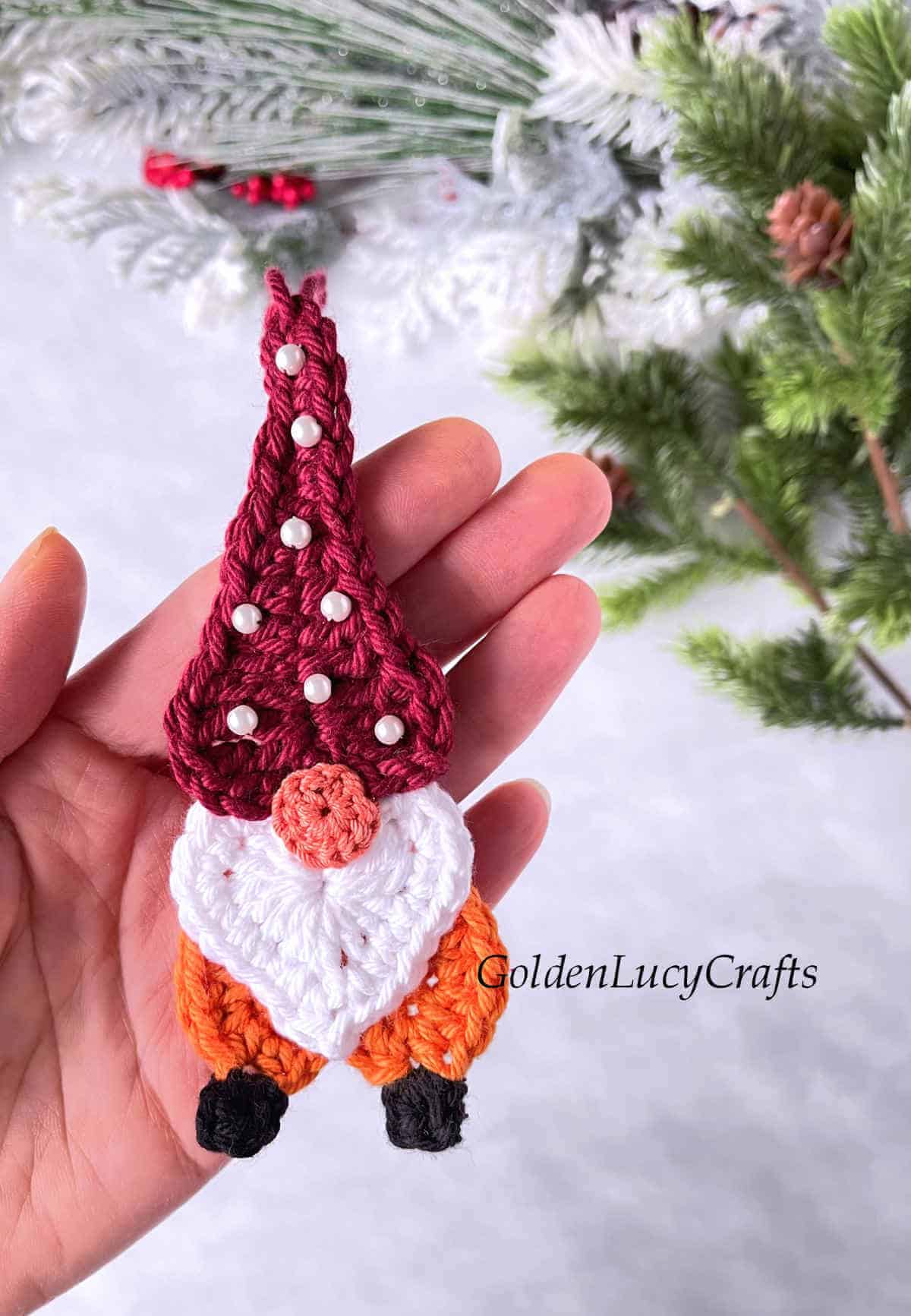 Crochet gnome ornament made from hearts in the palm of a hand.