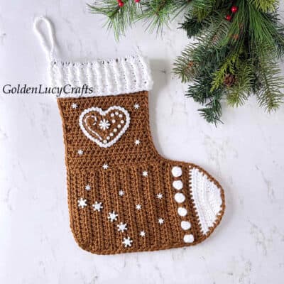 Crochet gingerbread Christmas stocking, Christmas tree branch in the background.