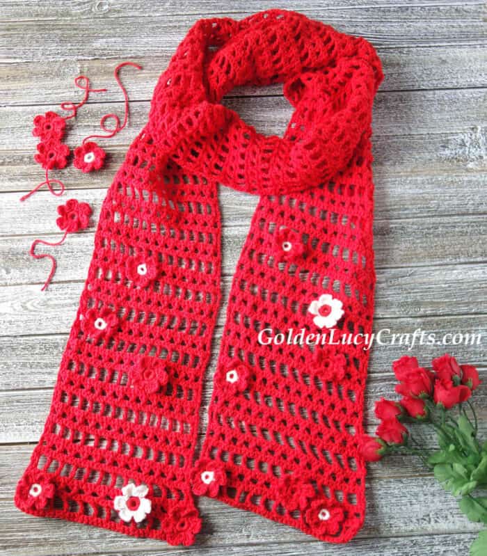 Crocheted red scarf embellished with flowers.