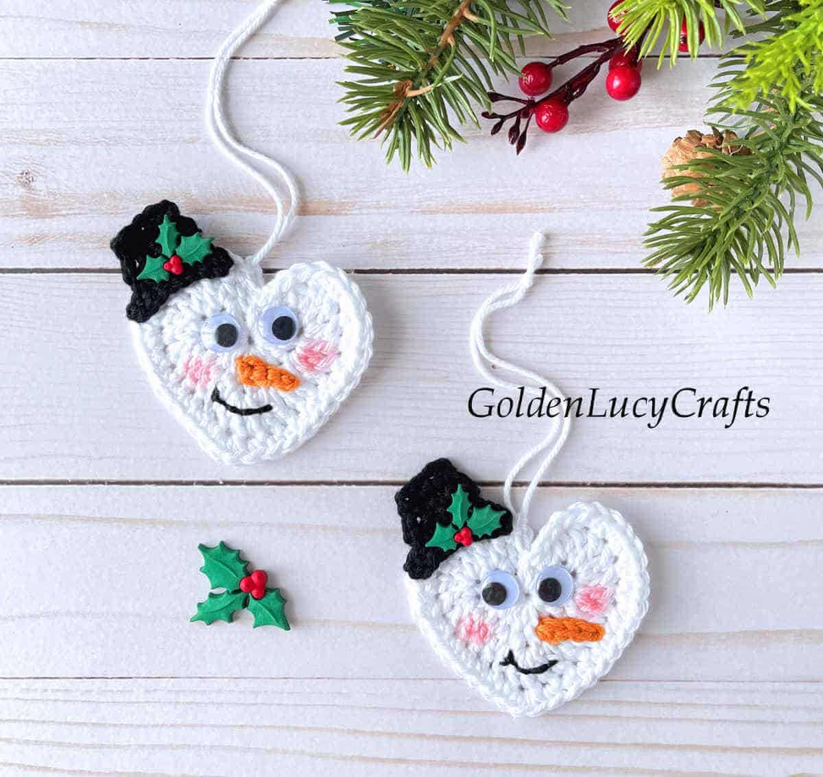 Two crochet heart-shaped snowman Christmas ornaments.