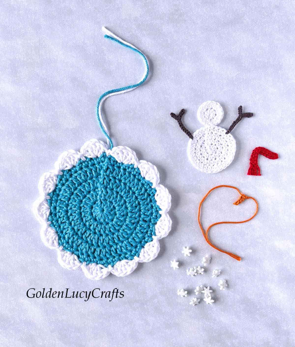 Parts of crochet winter ornament - base, snowman applique, snowflake buttons.