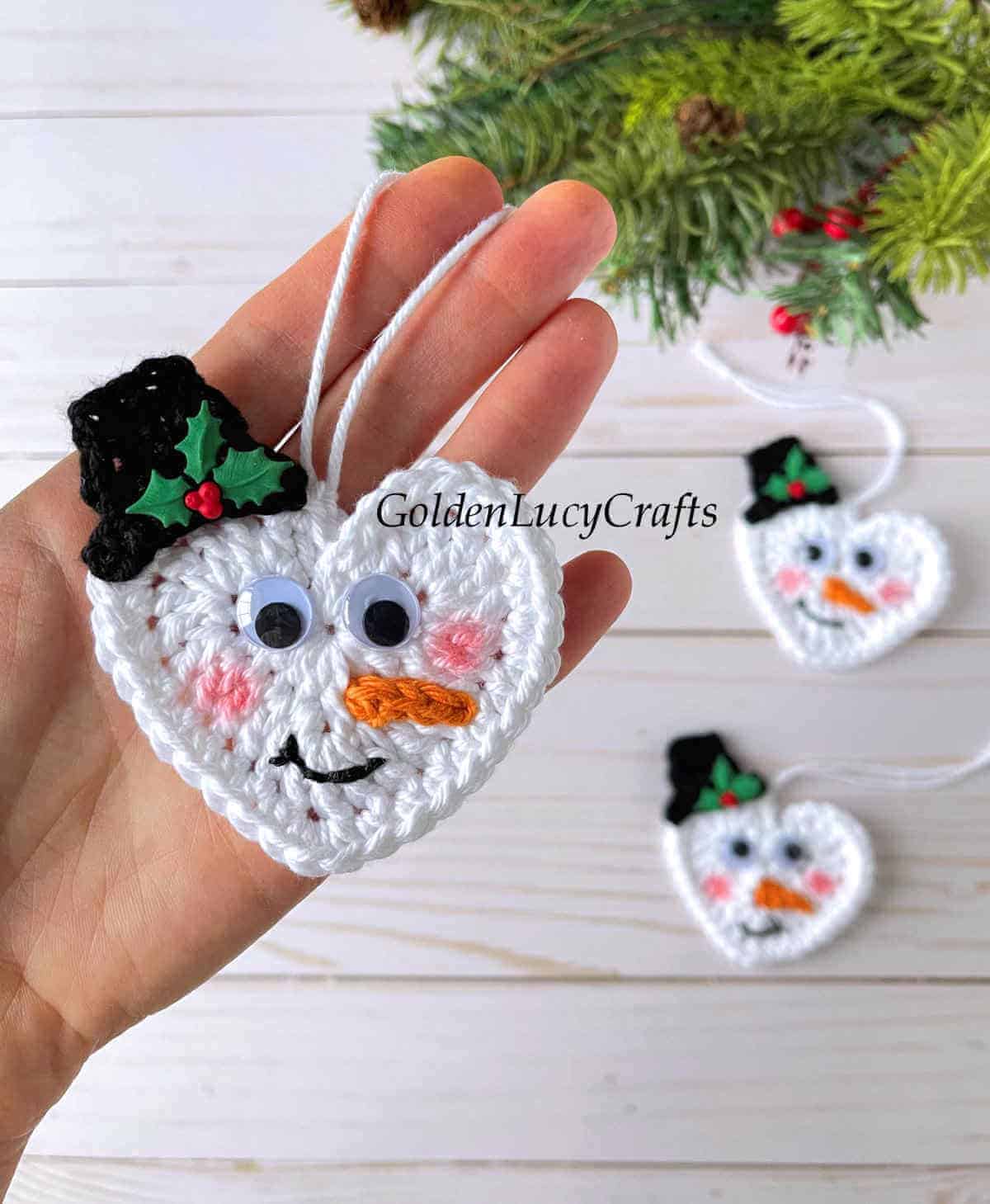 Crocheted heart snowman Christmas ornament in the palm of a hand.