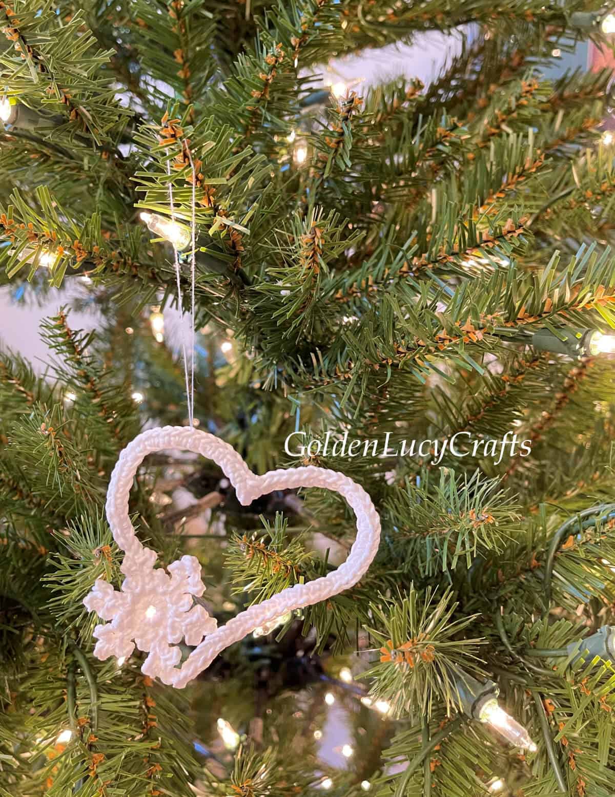Crochet snowflake heart ornament hanging on Christmas tree.