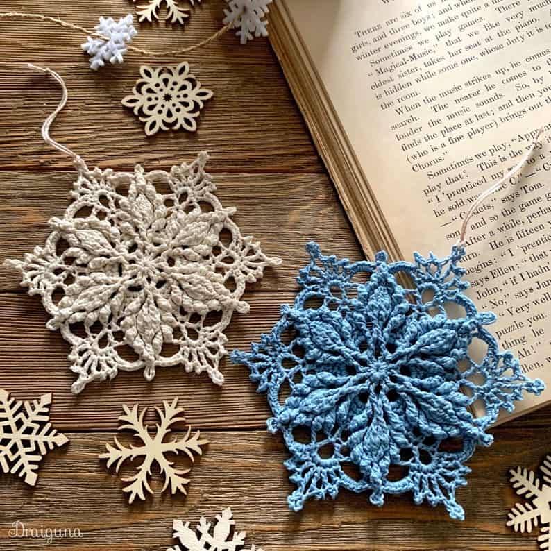 Two crocheted snowflake ornaments, small wooden snowflakes, open book.