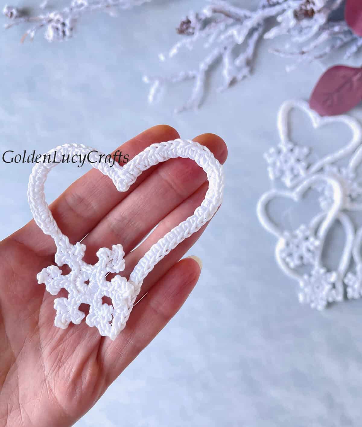 Crochet snowflake heart in the palm of a hand.