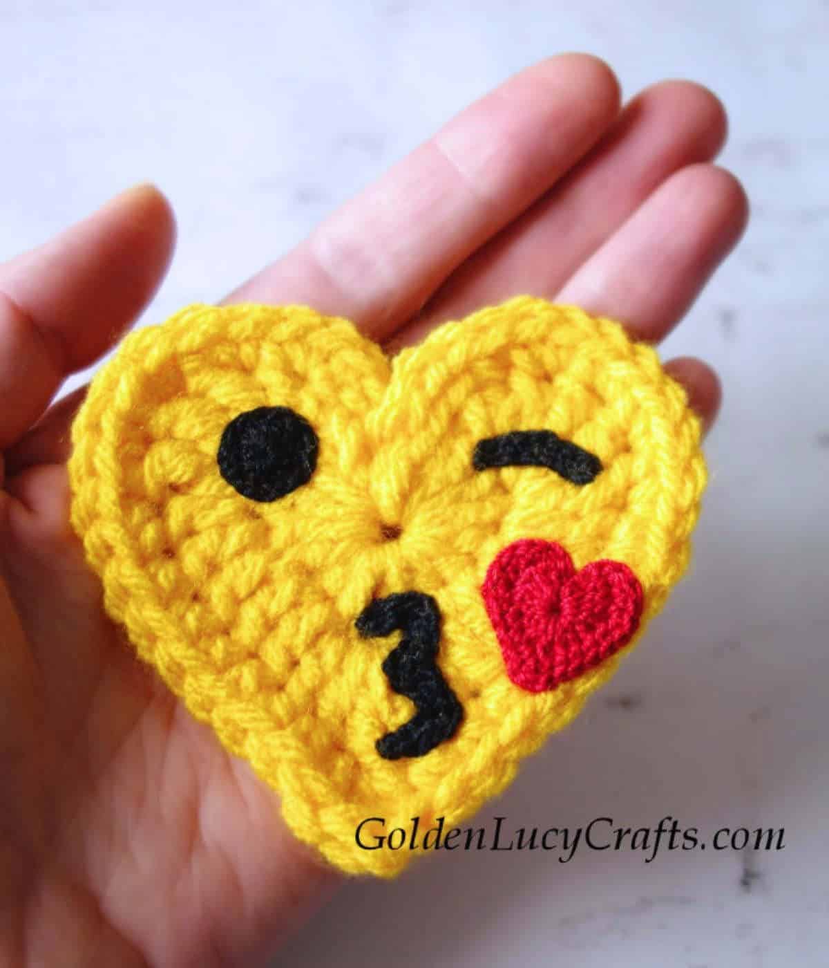 Crochet blowing a kiss emoji in the palm of a hand.
