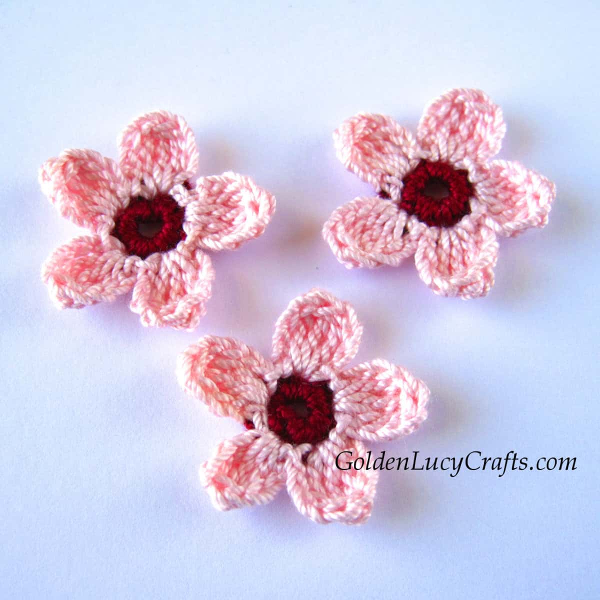 Three crocheted cherry blossom flowers.
