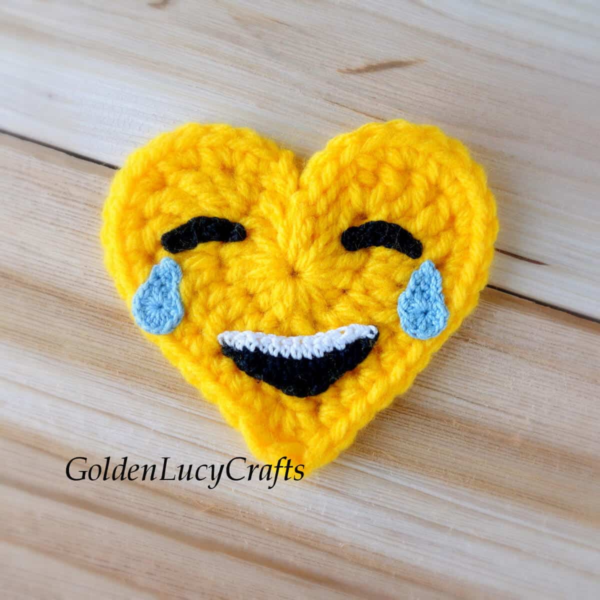 Crocheted heart-shaped tears of joy emoji.