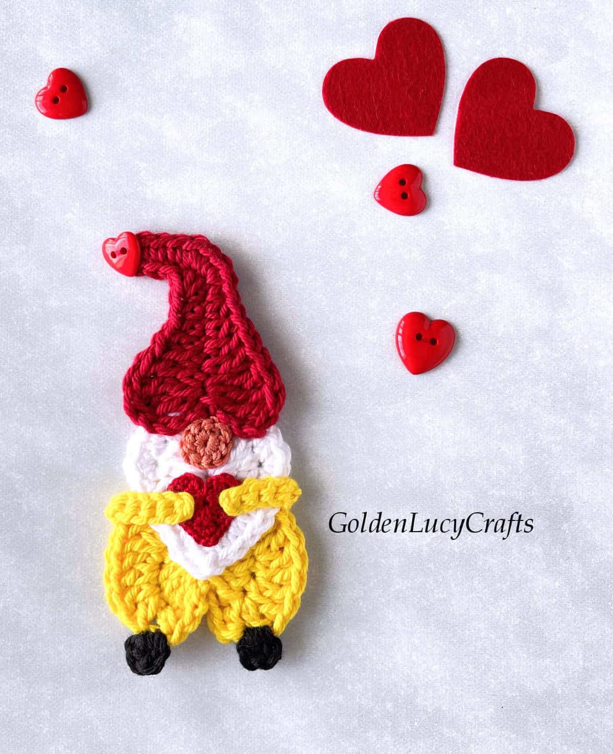 Crocheted gnome applique with heart in his hands.