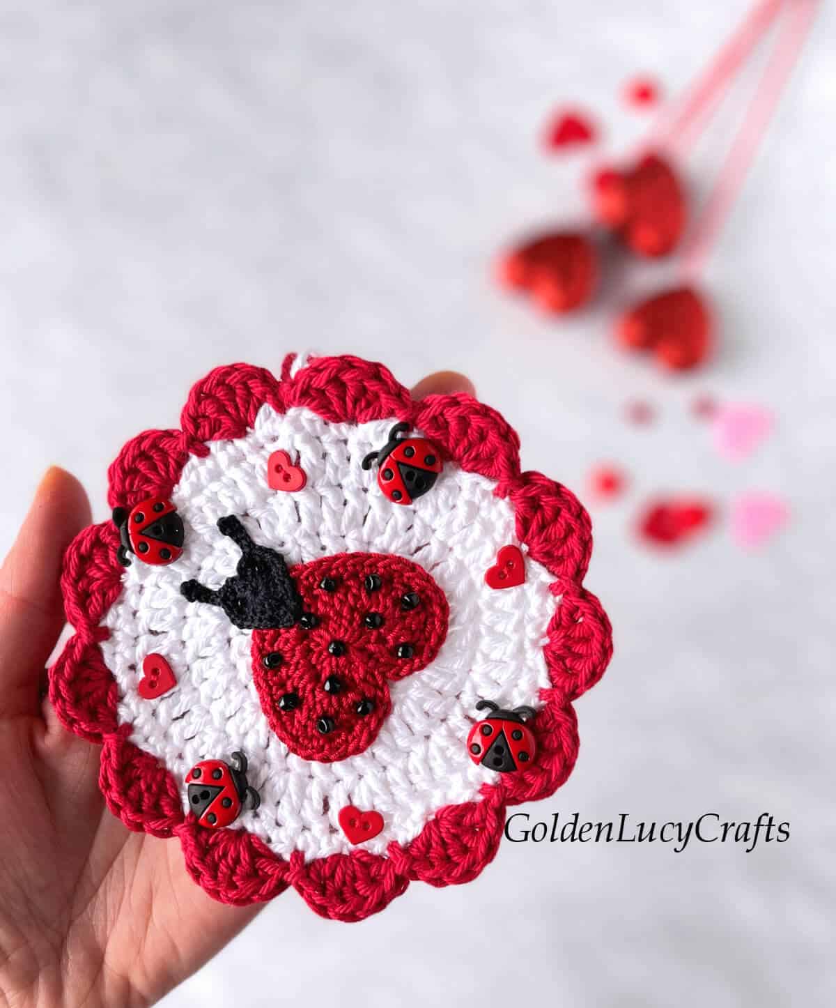 Crochet ladybug ornament in the palm of a hand.