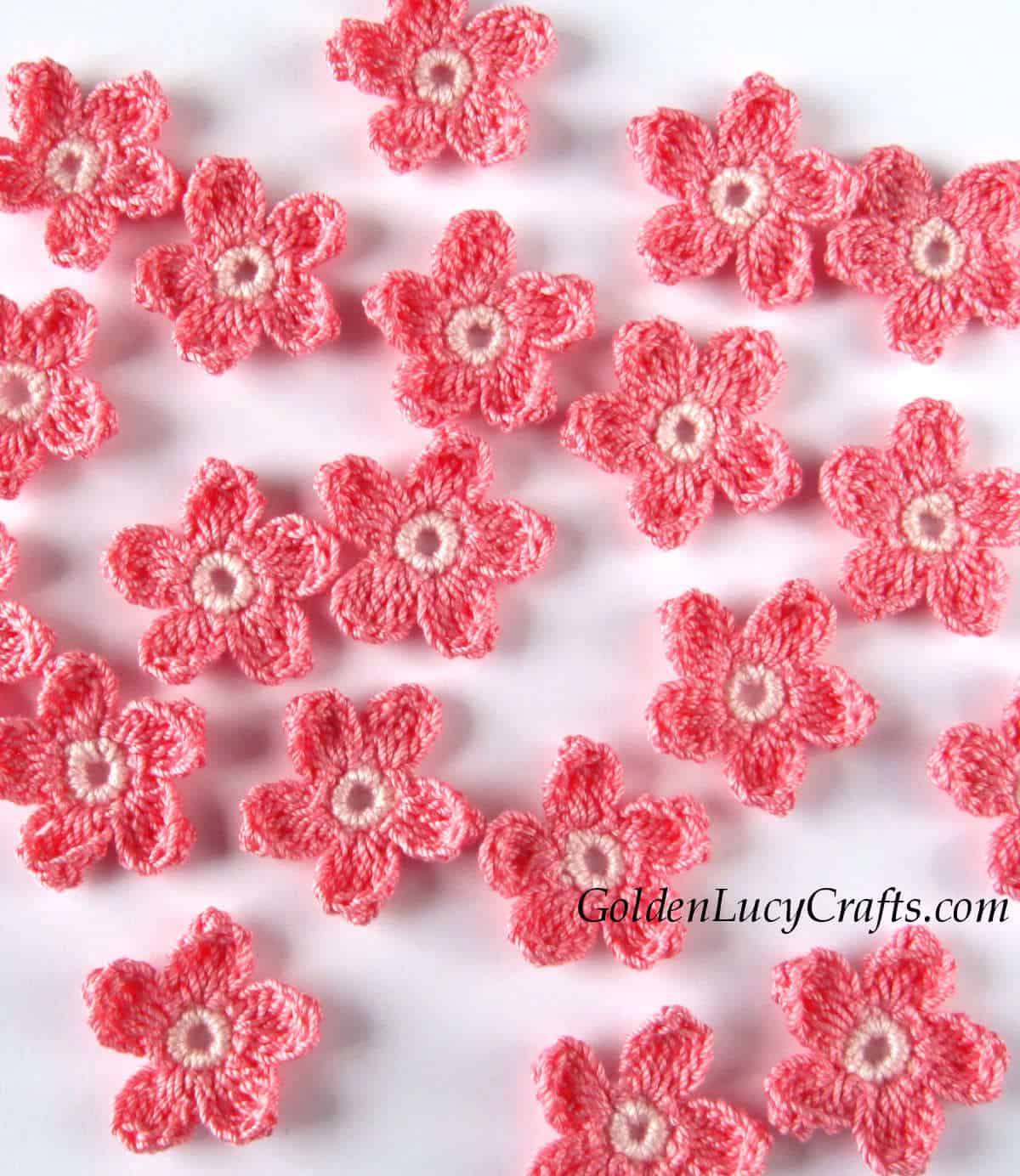 Crocheted small flowers in coral pink color.