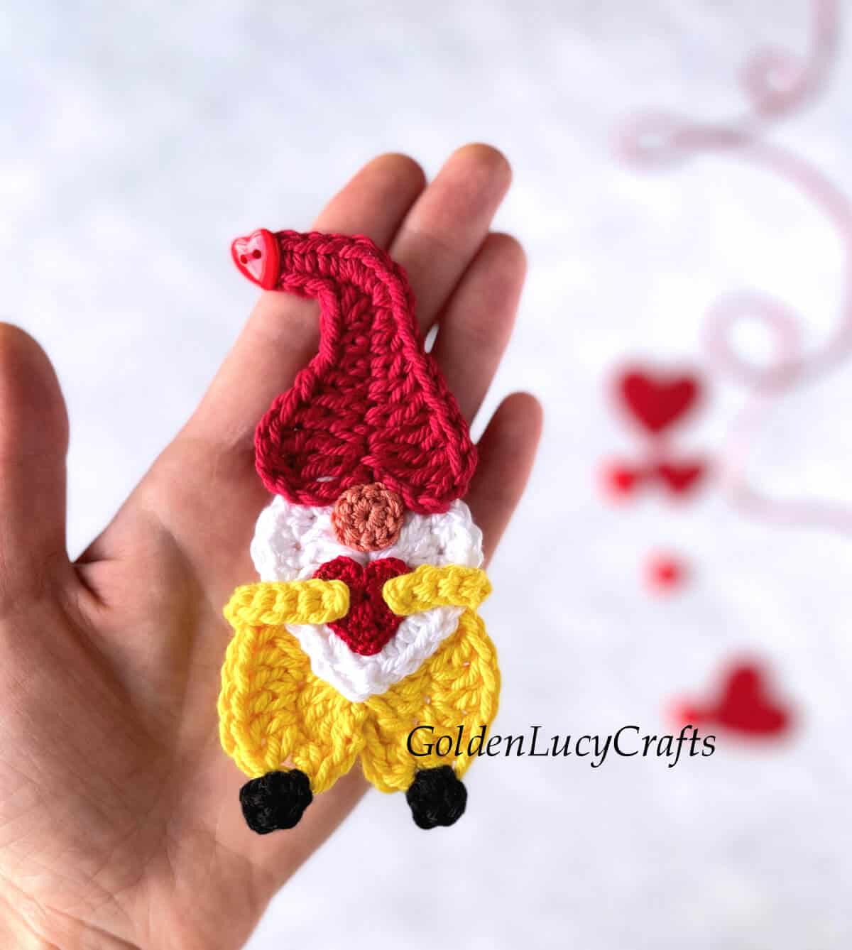 Crochet Valentine's Day gnome applique in the palm of a hand.