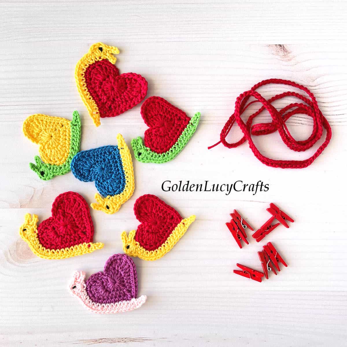 Crocheted snail appliques, red small clothespins, red string.