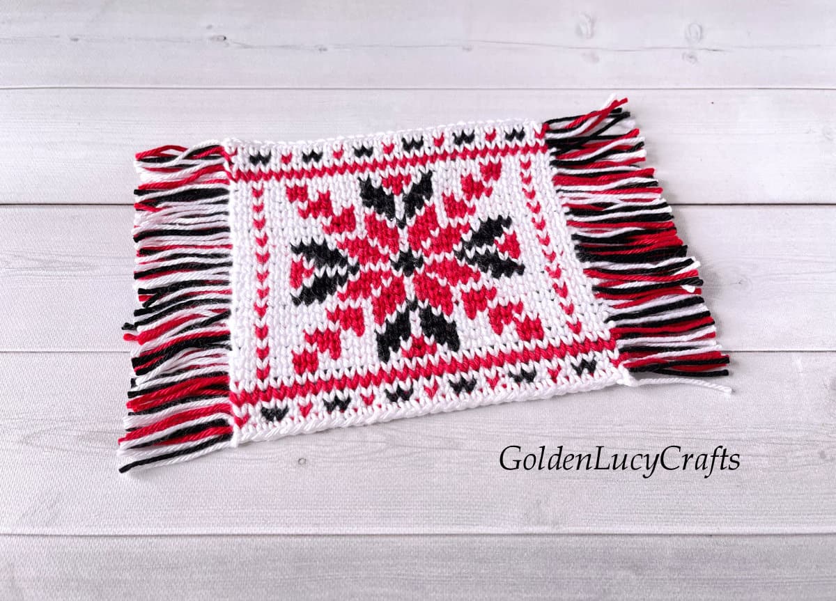 Crochet mug rug in red, black and white colors.