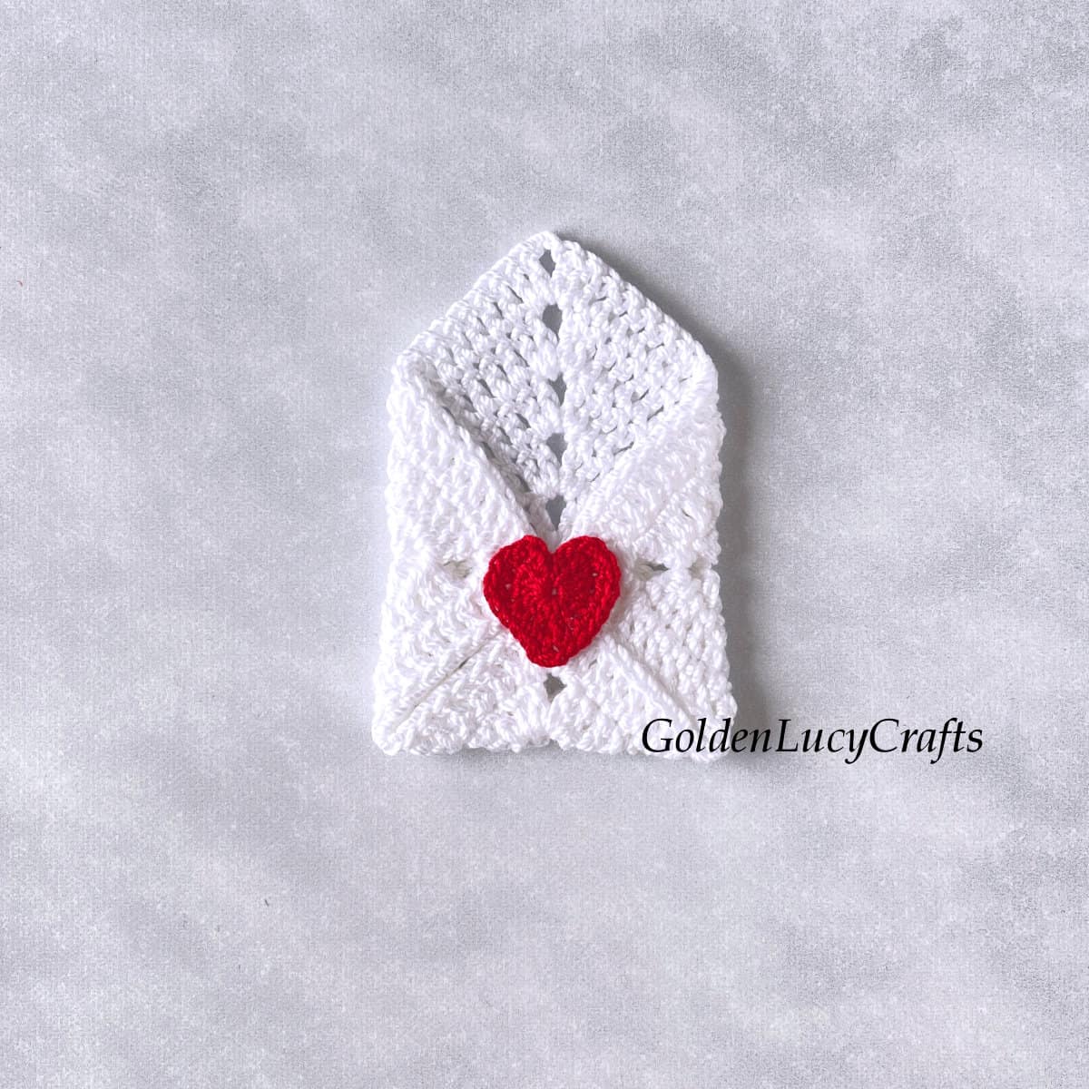 Crochet white envelope with red heart seal.