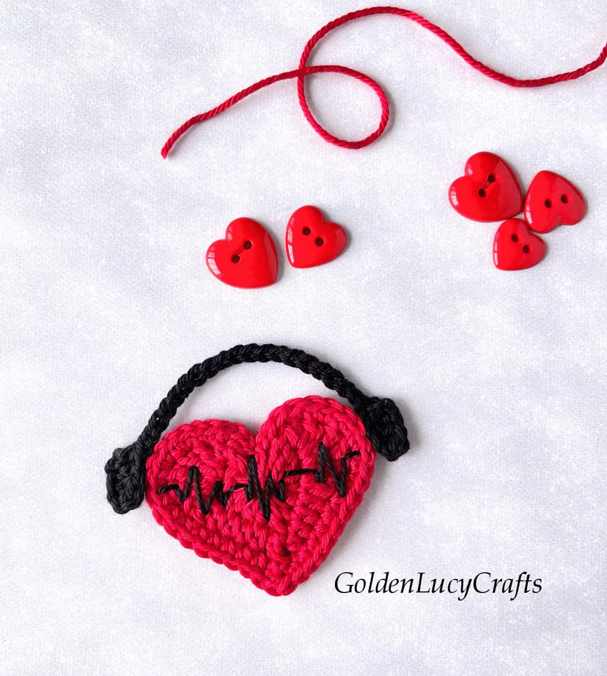 Crochet red heart with headphones and embroidered heartbeat.