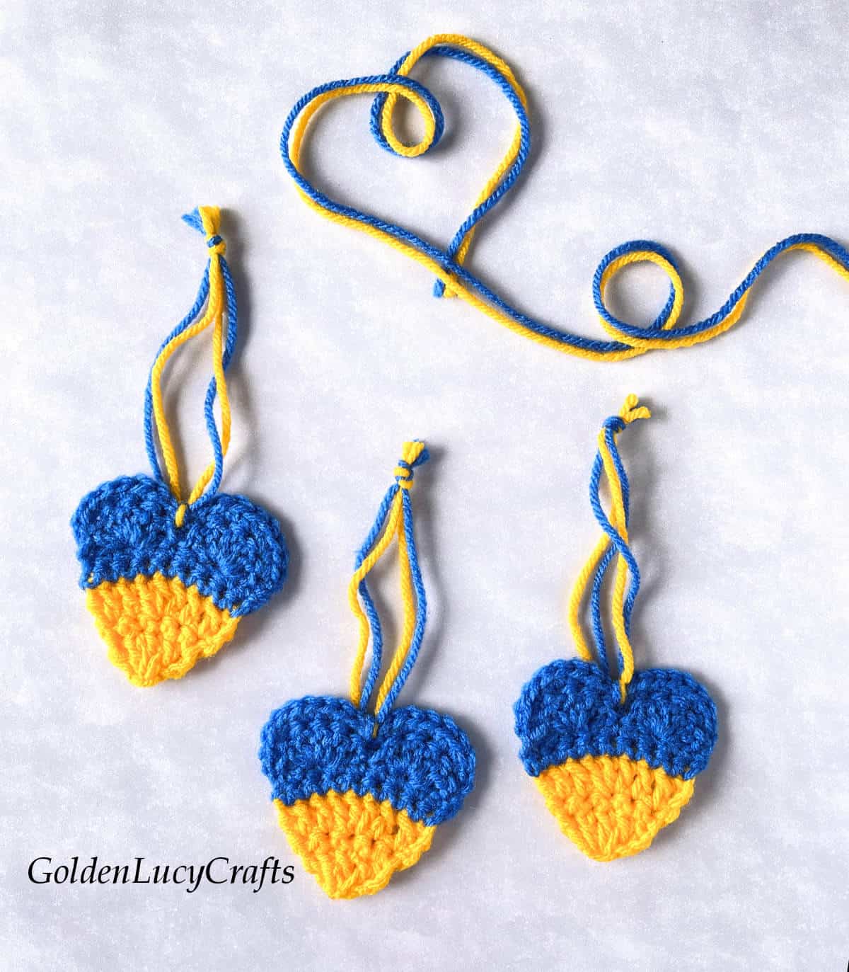 Three crocheted yellow blue hearts.