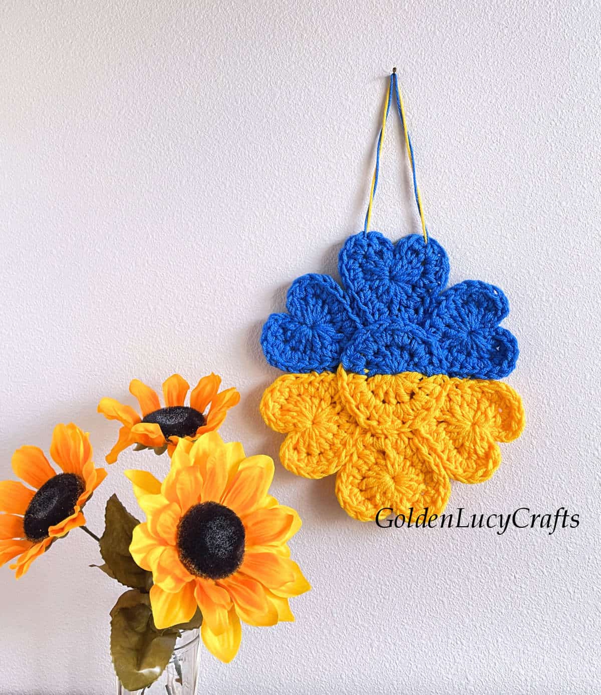 Crochet Ukrainian sunflower ornament hanging on the wall.