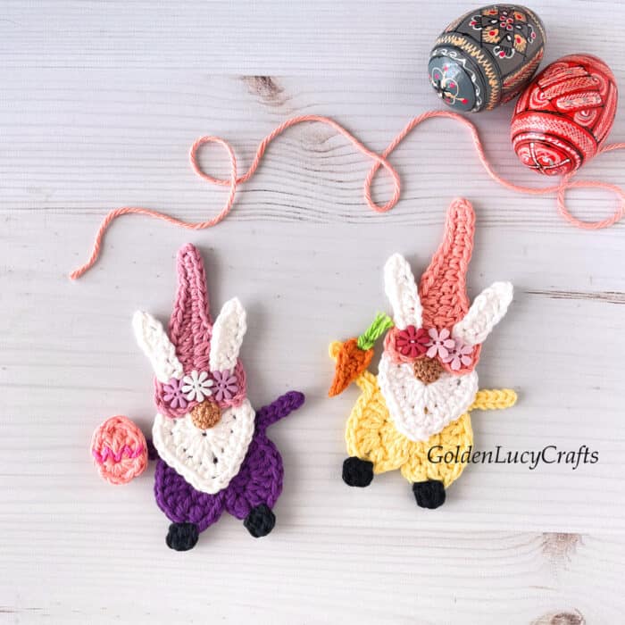 Two crochet Easter gnomes, decorated Easter eggs in the background.