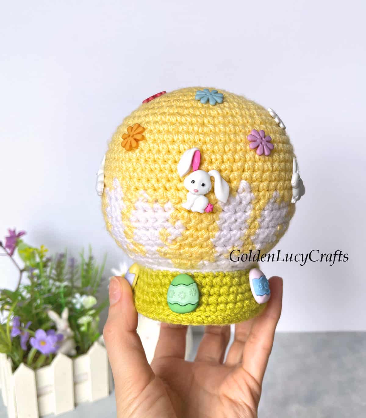 Crochet Easter snow globe held by finger tips.