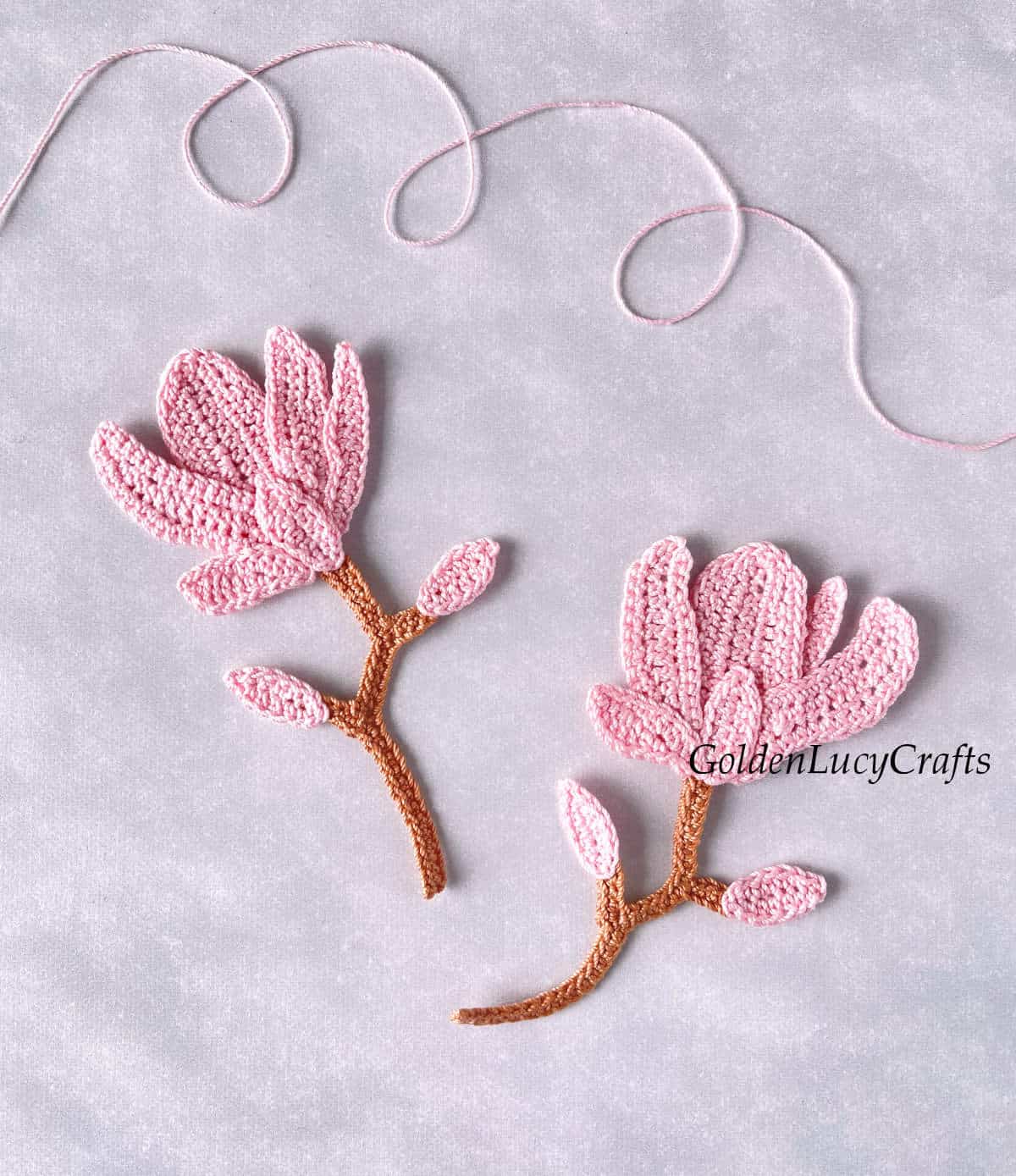Two crocheted magnolia flowers.