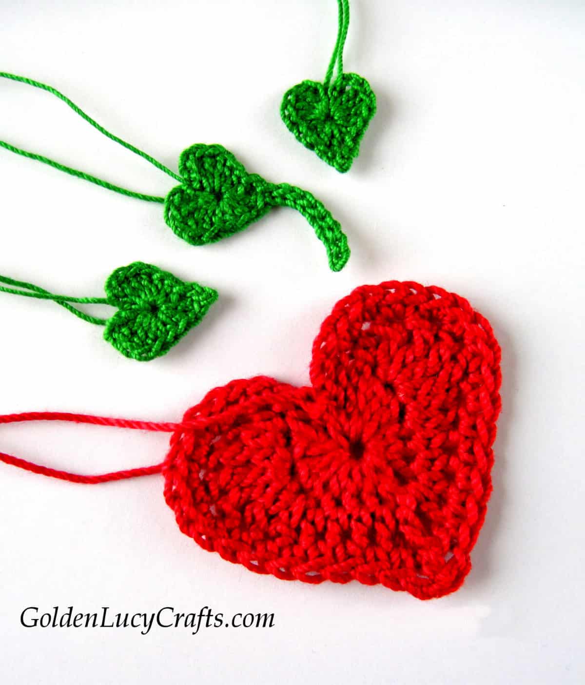 Crocheted one large red heart and three small green hearts, elements of strawberry applique.