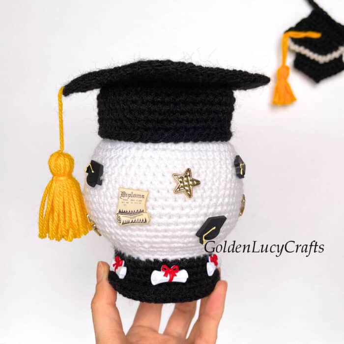 Crochet graduation snow globe help by fingertips.