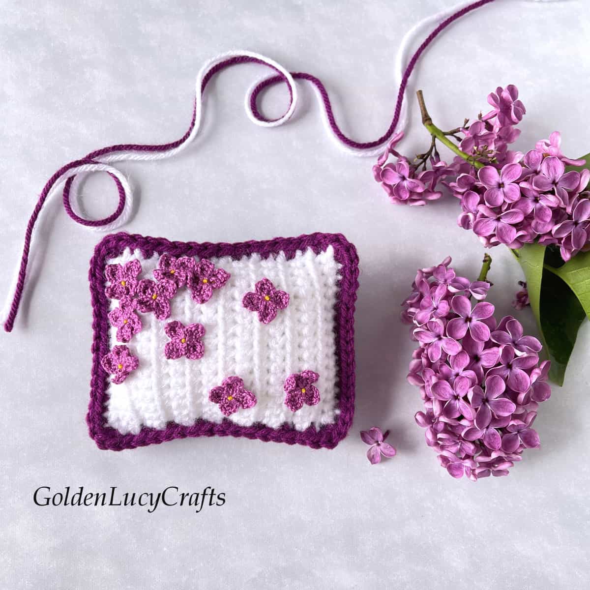 Crochet mini pillow - pincushion embellished with lilac flowers.