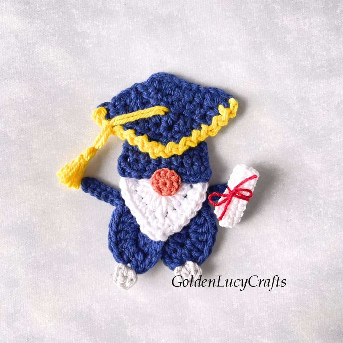 Crochet graduation gnome with diploma scroll.