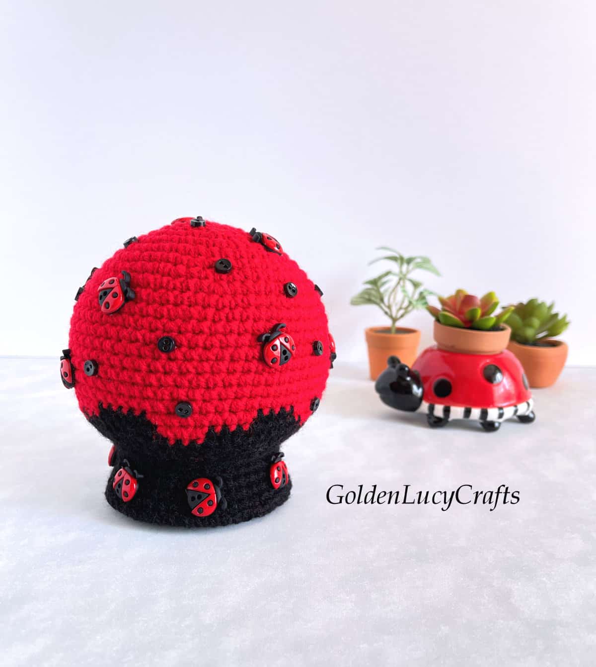 Crochet snow globe made in red and black colors and embellished with ladybug buttons and small black buttons.