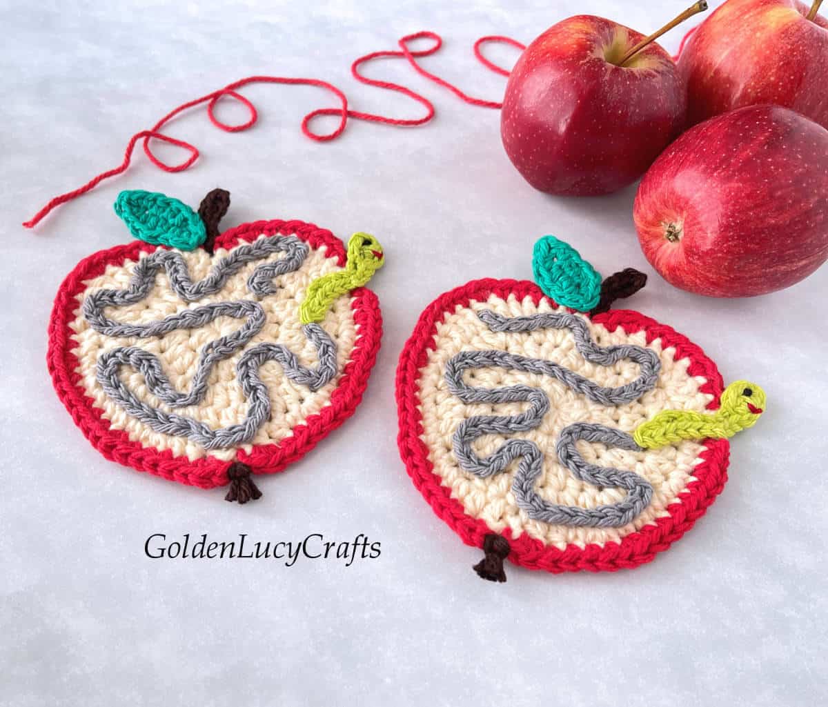 Two crocheted apple with worm coasters.