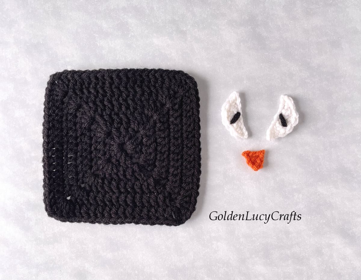 Crocheted black square, eyes and nose.