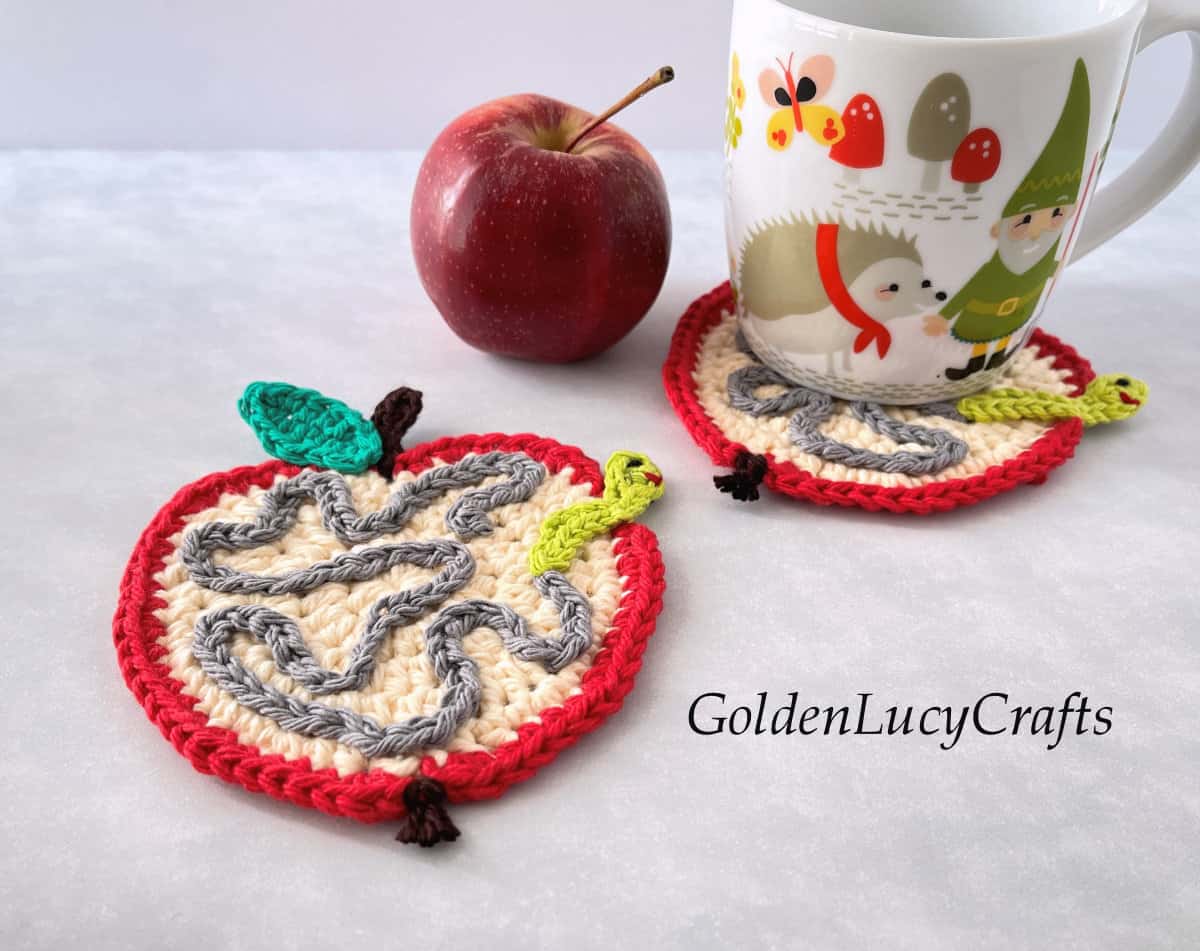 Crochet coasters apple with worm tunnel and small worm.