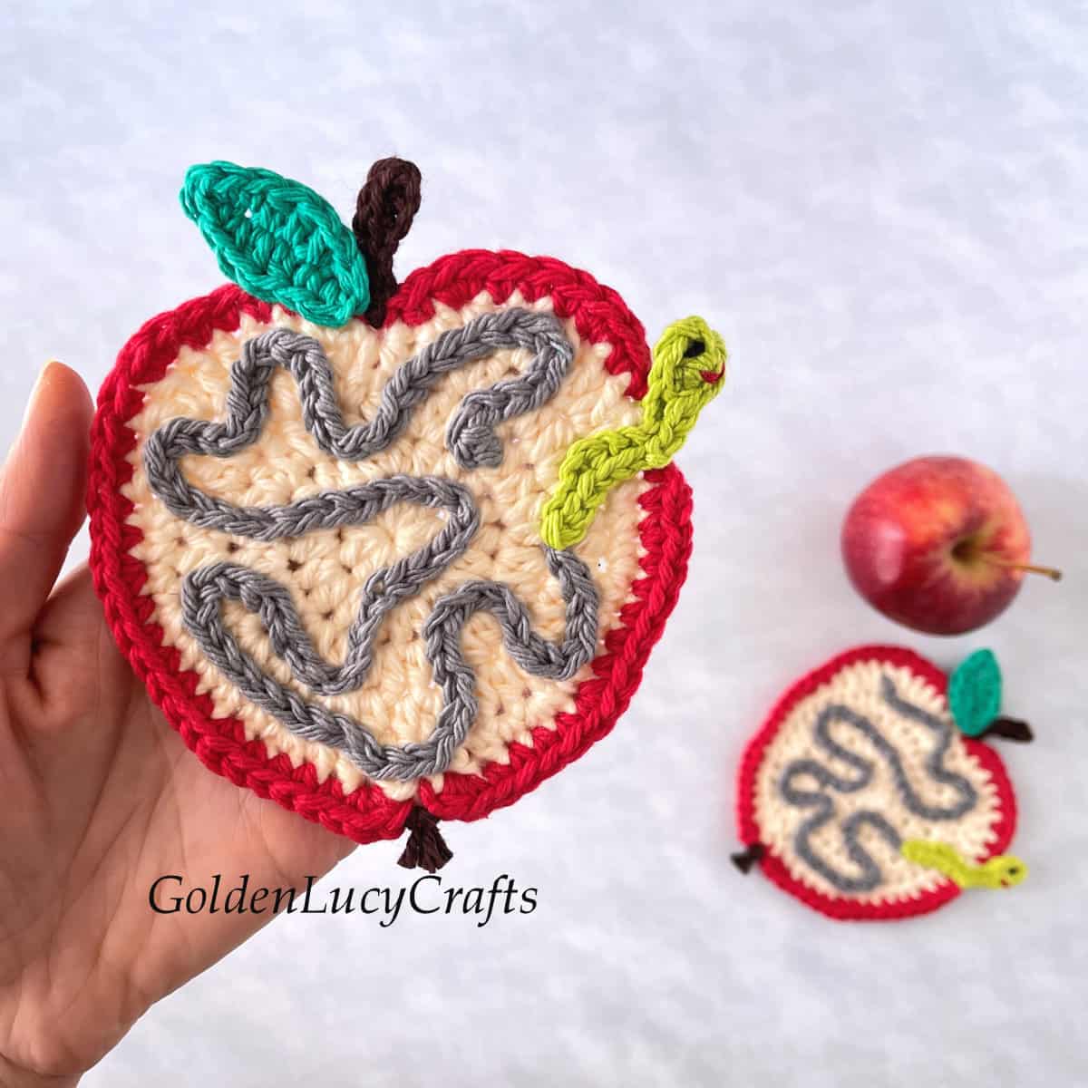 Crochet apple coaster in the palm of a hand.