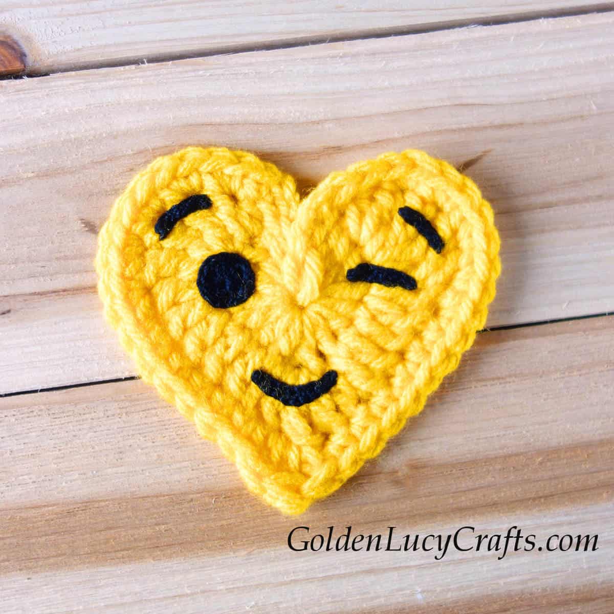 Crochet heart-shaped emoji winking face.