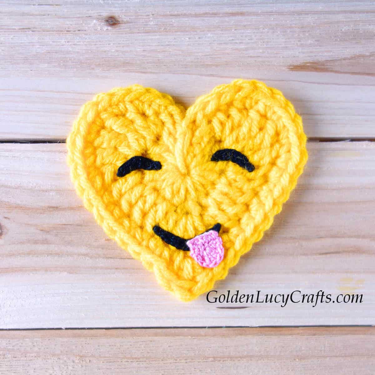 Crochet heart-shaped emoji savoring food.