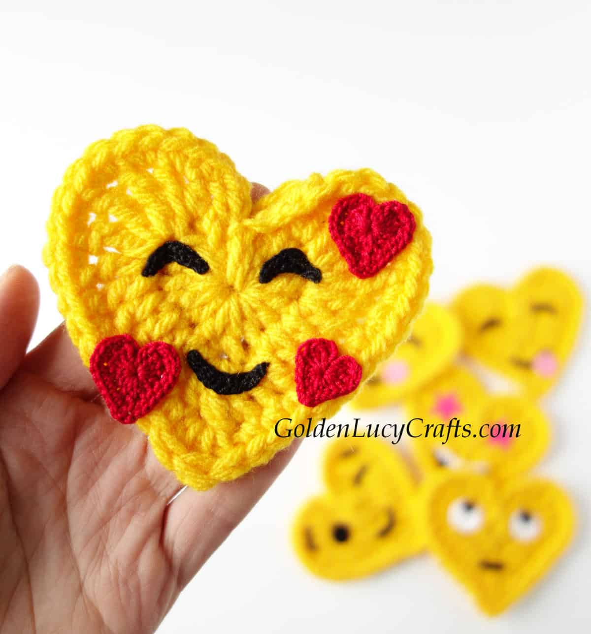 Smiling face crochet emoji in the palm of a hand.