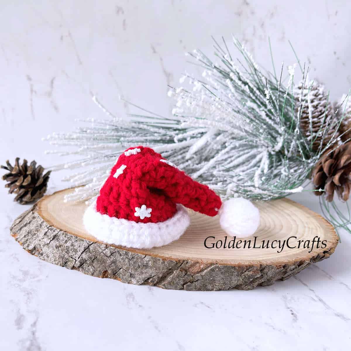 Crochet mini Sata hat on wood slice.