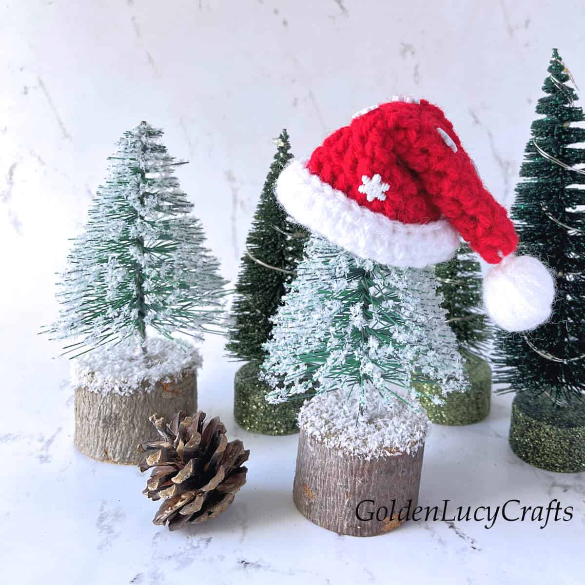 Crochet mini Santa hat on top of the miniature Christmas tree.