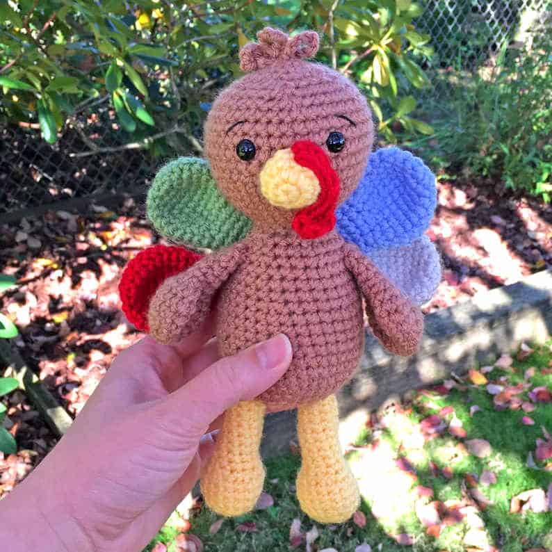 Crochet turkey toy held by a hand.