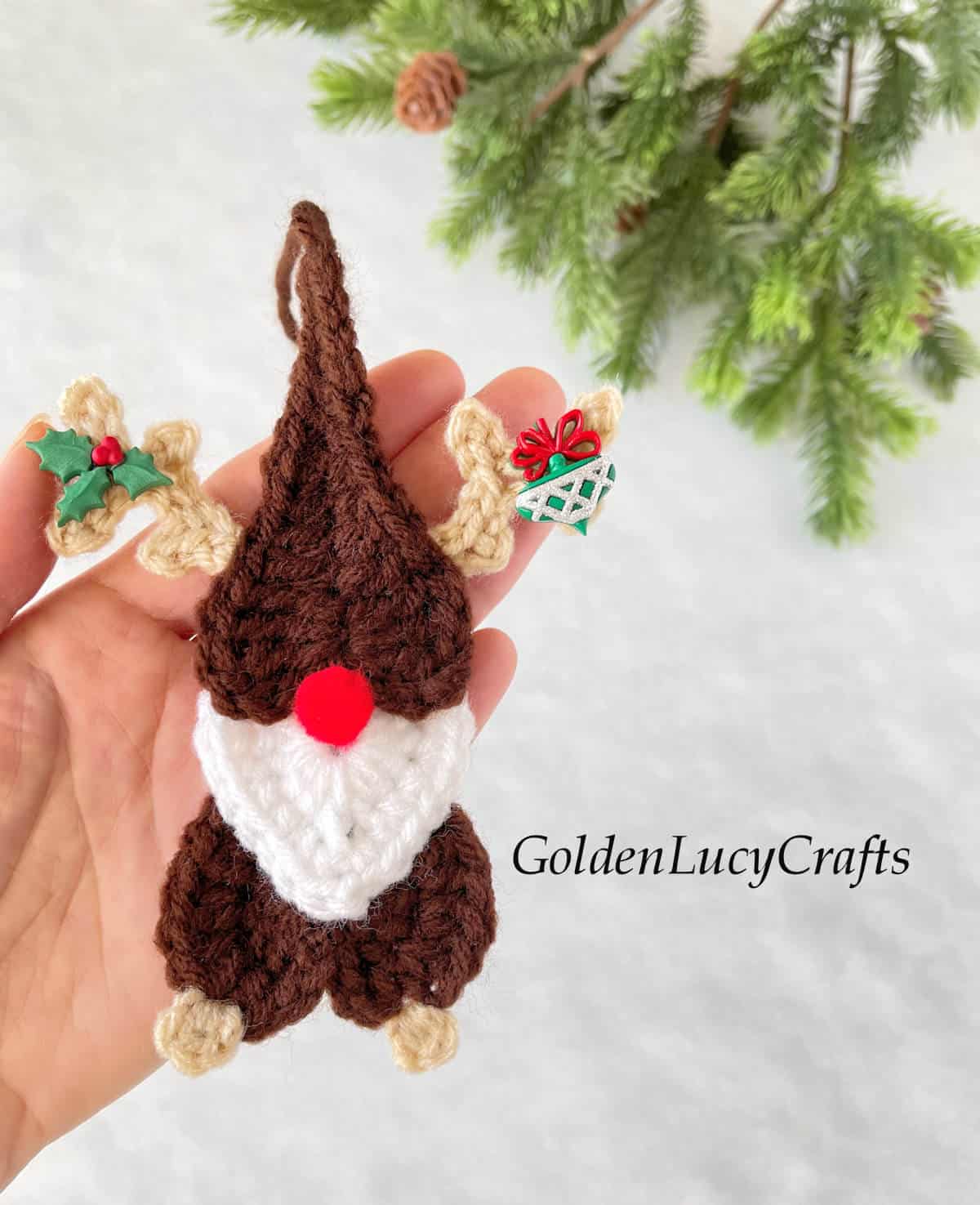 Crochet Christmas ornament reindeer gnome in the palm of a hand.