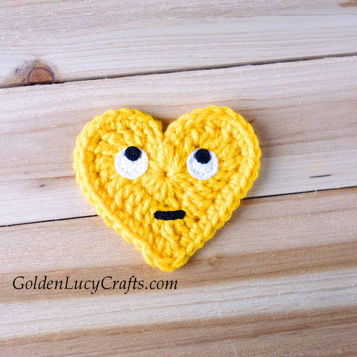 Crochet heart-shaped emoji rolling eyes.