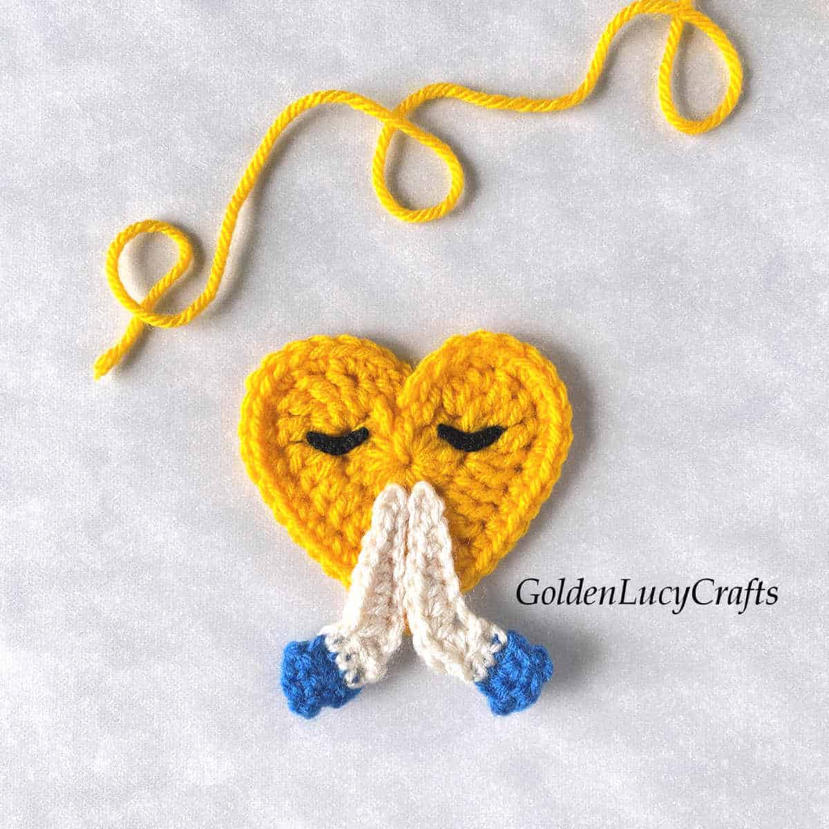 Crochet praying hands heart-shaped emoji.