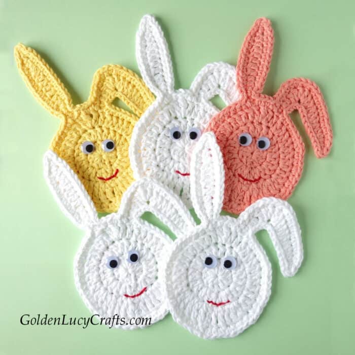 Five crocheted Easter bunny faces with googly eyes.