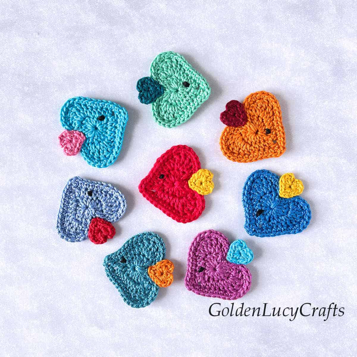Eight crocheted heart-shaped fish appliques.