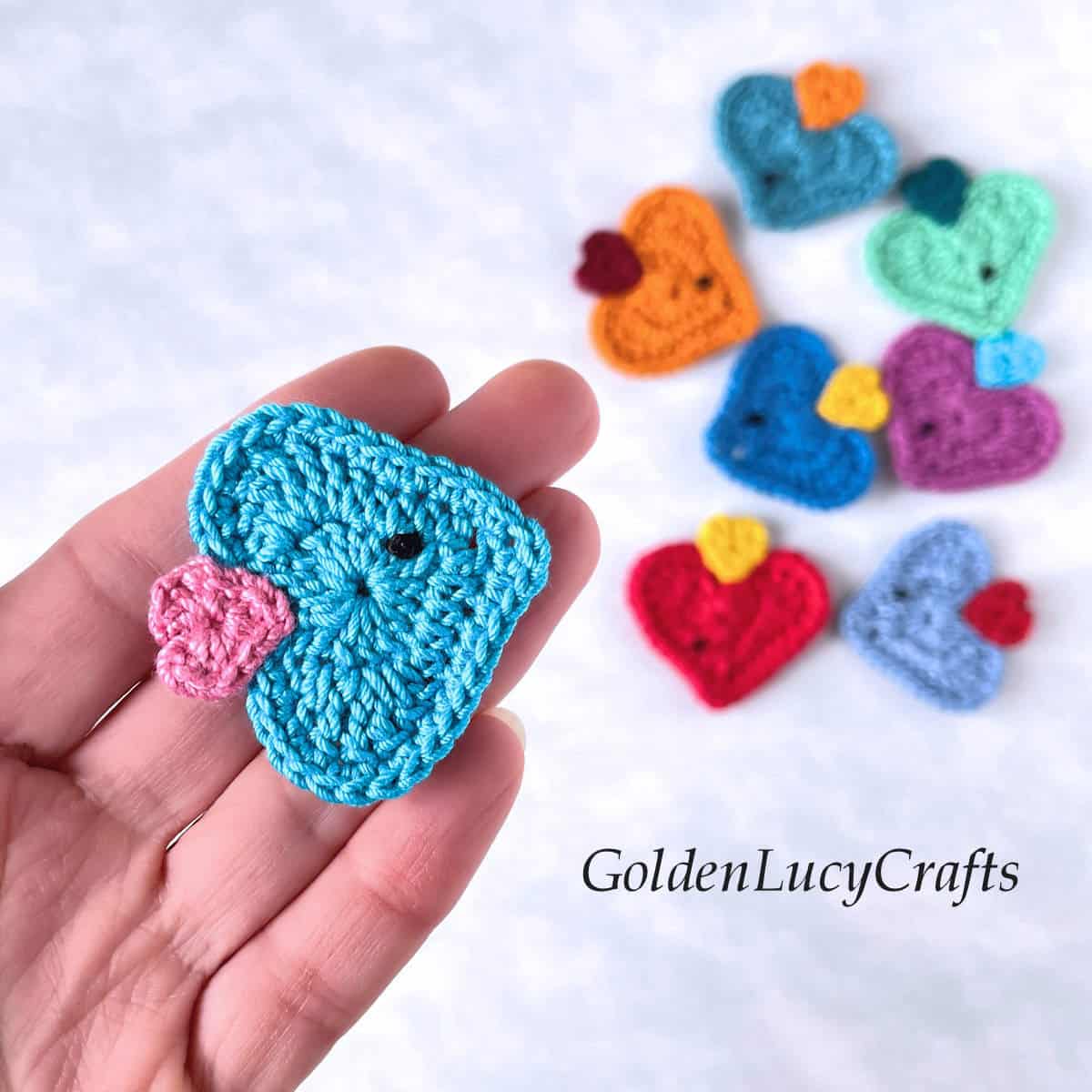 Crochet heart fish applique in the palm of a hand.