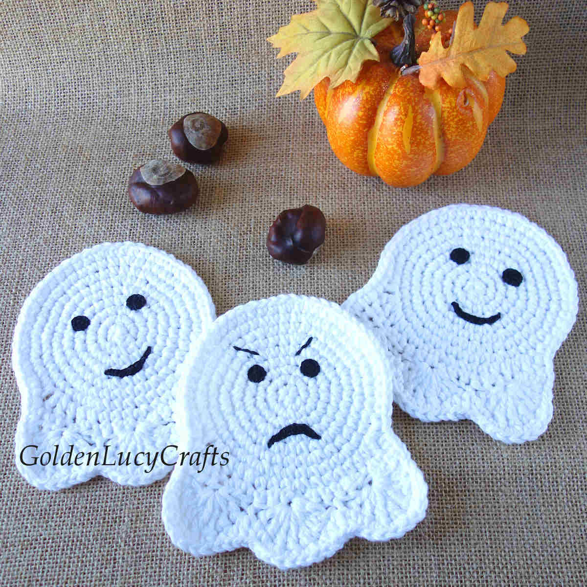 Three crocheted ghost coasters, pumpkin in the background.