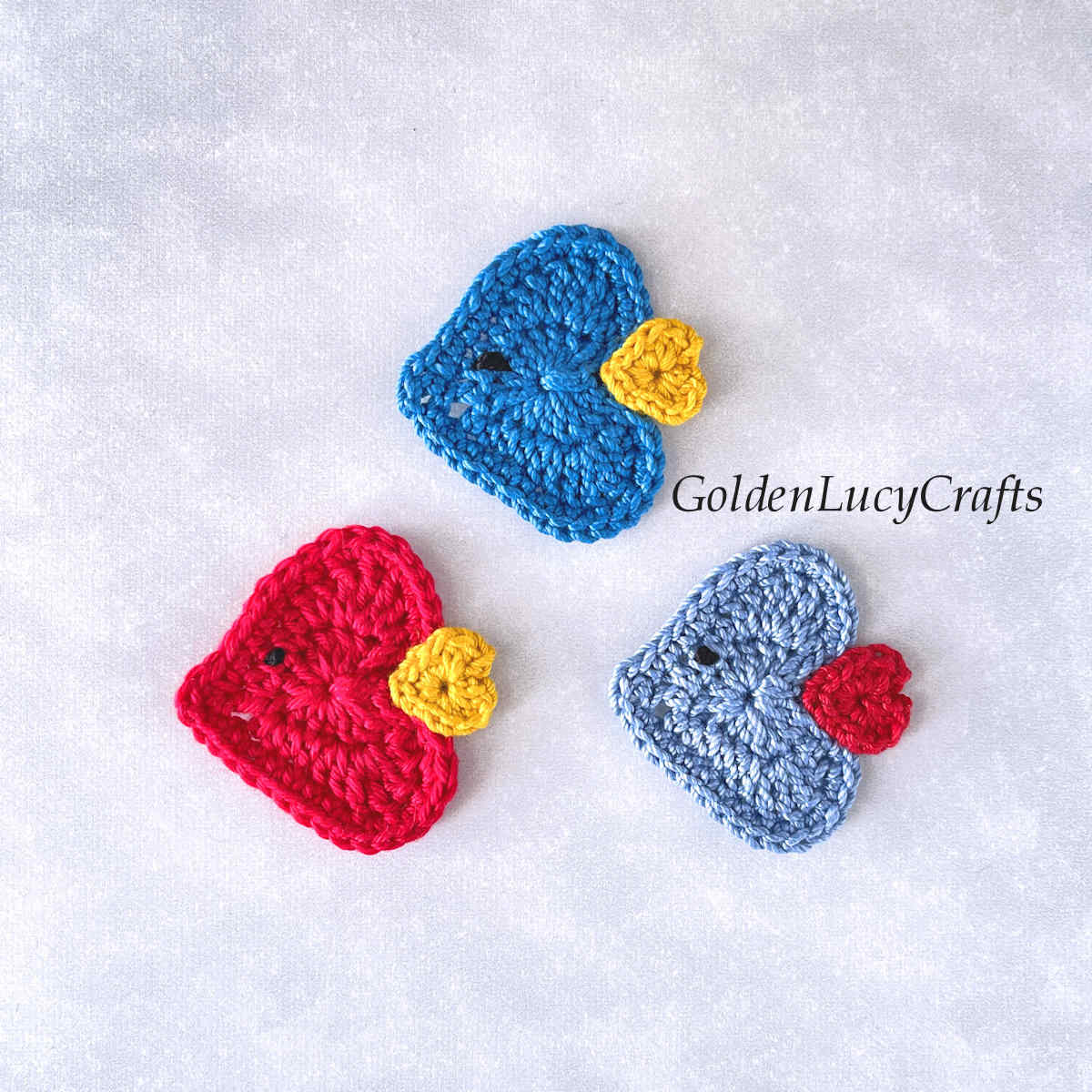 Three crochet heart-shaped fish appliques.