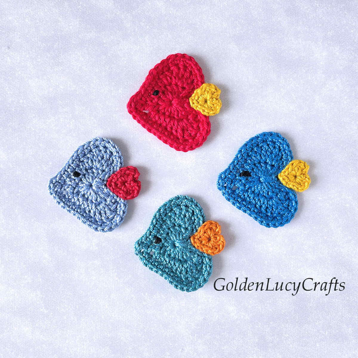 Four crocheted heart-shaped fish appliques.