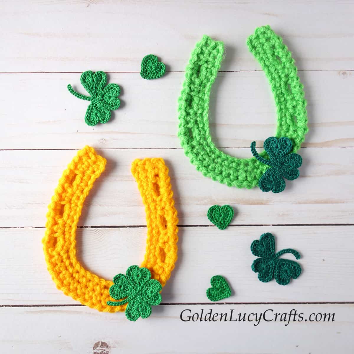 Two crocheted horseshoe appliques embellished with clovers.